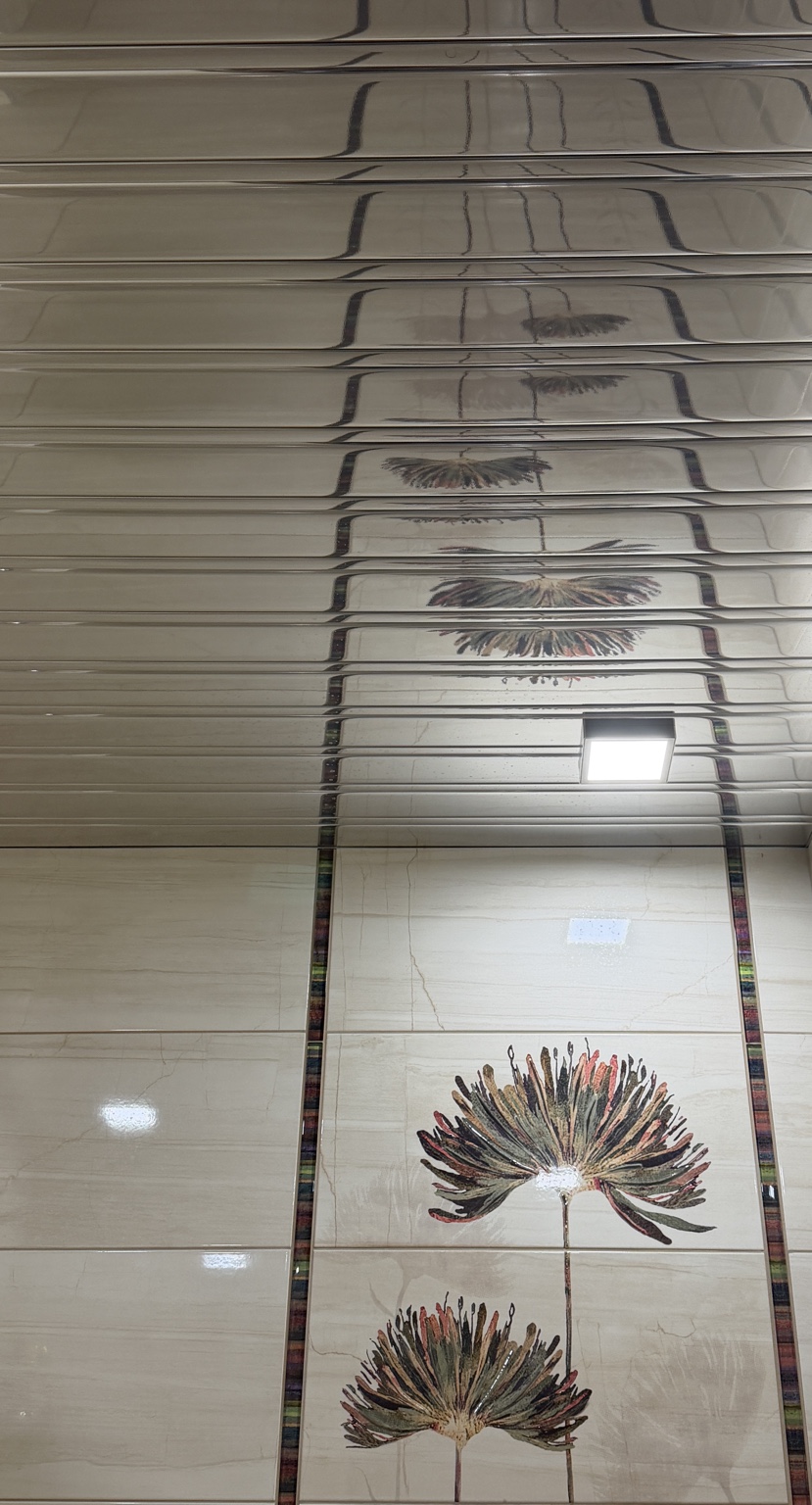 Installed reflective metal ceiling above decorative floral wall tiles